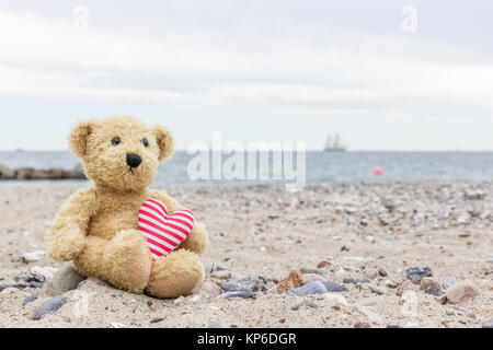 Un orsacchiotto di peluche con il mio cuore si siede sulla spiaggia del Mar Baltico Foto Stock