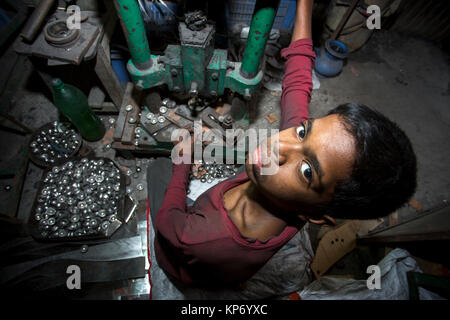 Un bambino fatiche stanno lavorando la sfera di acciaio rendendo fabbrica. Foto Stock