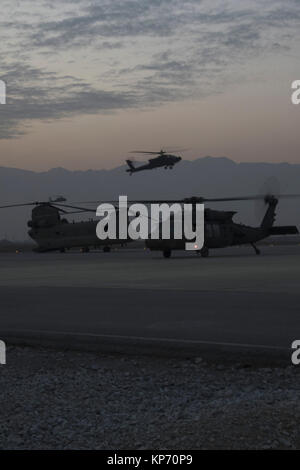 Come il sole tramonta, un AH-64 Apache e UH-60 Black Hawk elicottero di ritorno da una missione in Afghanistan settentrionale Dicembre 9, 2017. L'elicottero e il suo equipaggio sono parte della Task Force Brawler, 4° Battaglione, 3° Reggimento di aviazione, fuori di Savannah, Georgia, operazioni di supporto per le forze di terra del comandante in Afghanistan. (US Army Foto Stock