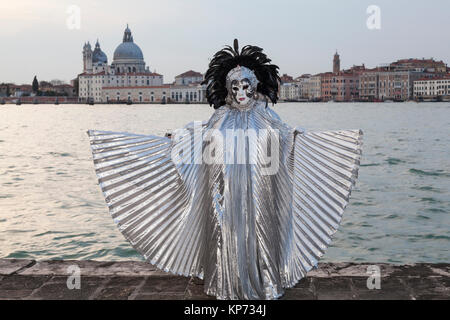 Il Carnevale di Venezia 2017, Veneto, Italia donna con extended silver wings e Basilica di Santa Maria della Salute al tramonto Foto Stock