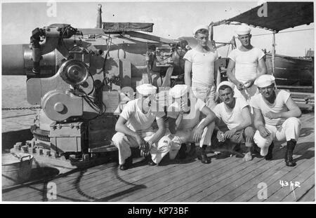 Un equipaggio di marinai a bordo di un cacciatorpediniere americano di fronte a cinque pollici pistola. Due marinai di fumare sigarette. Foto Stock