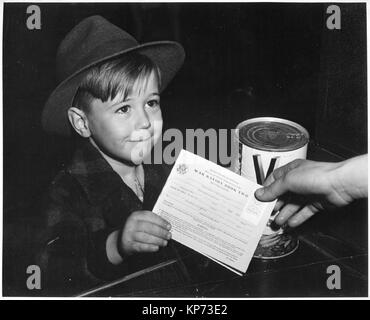 Un ansioso ragazzo scuola ottiene la sua prima esperienza di utilizzo di razione di guerra di prenotare due. Con molti genitori impegnati nel lavoro di guerra i bambini vengono insegnati i fatti del punto di razionamento per aiutare in famiglia marketing., ca. 02/1943 Foto Stock