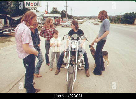 Uomo sulla Harley Davidson Moto si ferma a parlare con gli amici nei primi anni settanta (piccola cittadina in Texas) Foto Stock