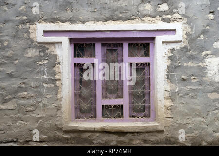 Finestra con viola il telaio in legno sul muro esterno di una casa tibetana in Kagbeni, Mustang superiore, Nepal. Foto Stock