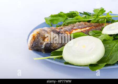 Vista dettagliata di pesce alla griglia e servita con verdure verdi e cipolla. Foto Stock