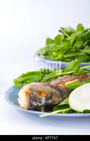 Vista dettagliata di pesce alla griglia e servita con verdure verdi e cipolla. Foto Stock