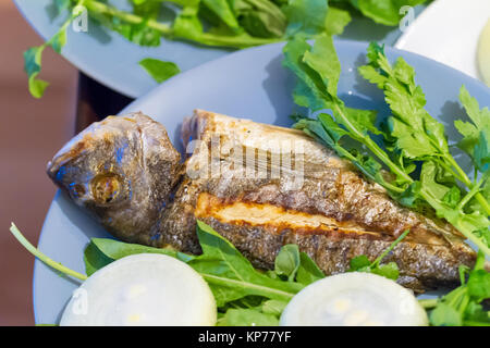 Vista dettagliata di pesce alla griglia e servita con verdure verdi e cipolla. Foto Stock