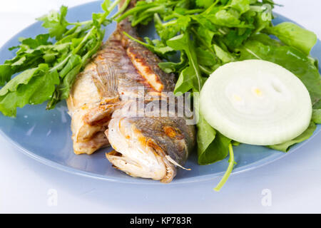 Vista dettagliata di pesce alla griglia e servita con verdure verdi e cipolla. Foto Stock