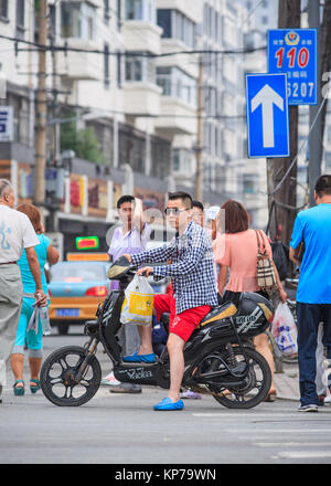 CHANGCHUN-luglio 8, 2013. Moda giovane uomo su un e-bike. Molte delle bici elettriche in Cina sono in stile di scooter e bici che possono o non possono avere i pedali. Foto Stock