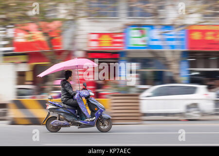 Di YIWU-cina-gen. 15, 2016. Uomo cinese su uno scooter elettrico. Grazie al governo di incoraggiamento e di una popolazione ben ferrati a cavallo di due ruote per wor Foto Stock