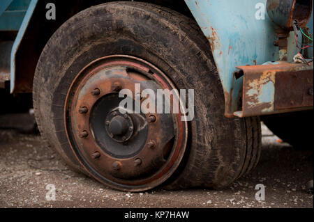 Vecchio rovinato carrello pneumatico, pneumatico sgonfio sulla ruota arrugginita Foto Stock