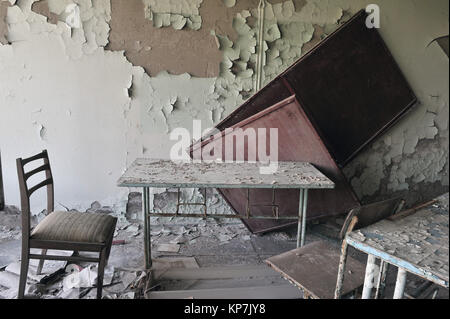 Distrutto in aula la scuola abbandonata in pripjat, il Consiglio è caduto il muro di un tavolo e sedie in polvere, cestino di Chernobyl, in Ucraina. Foto Stock