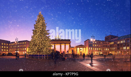 La Porta di Brandeburgo a Berlino con albero di Natale e la caduta di neve in serata. Panoramica immagine dai toni. Foto Stock