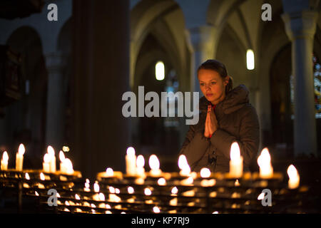 Giovane donna pregando in una chiesa Foto Stock