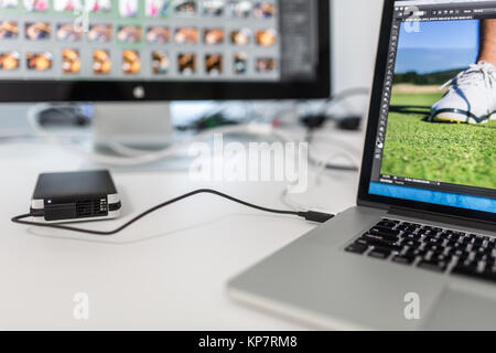 Fotografi computer con modifica foto apps/programmi in esecuzione - immagini essendo lavorato finemente sintonizzati a guardare i loro migliori. Il moderno equipaggiamento informatico in una foto in studio. Foto Stock