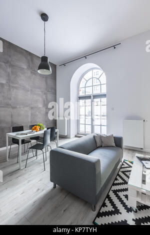 Spazio pranzo e confortevole divano grigio in moderno appartamento loft Foto Stock