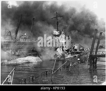 Fotografia navale di documentare l'attacco giapponese a Pearl Harbor, Hawaii che ha avviato la partecipazione degli Stati Uniti nella seconda guerra mondiale. La marina della didascalia: il ritorto rimane del cacciatorpediniere USS SHAW la masterizzazione in floating drydock a Pearl Harbor Foto Stock