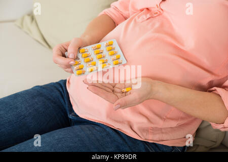 Donna incinta prendendo pillola di vitamina A CASA Foto Stock