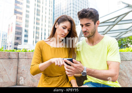 Coppia caucasica uso del cellulare all'aperto Foto Stock