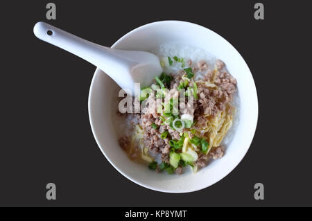 Soft boiled riso con carne macinata di maiale, congee nella ciotola bianco isolato su sfondo nero Foto Stock