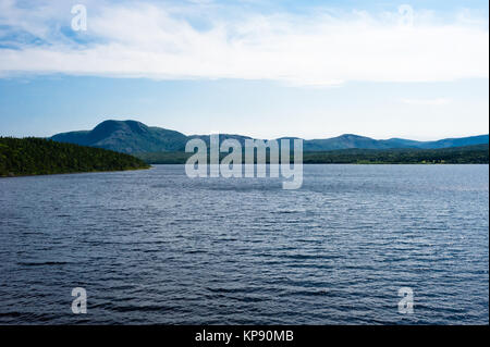 Lago tra colline coperte di boschi e montagna Foto Stock