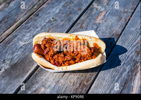 Hot Dog coperto di chili sulla tavola di legno Foto Stock