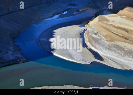 La confluenza del fiume Indo e Zanskar, due flussi di diversi colori si fondono, di un colore giallo brillante isola di sabbia di fiume, Ladakh. Foto Stock