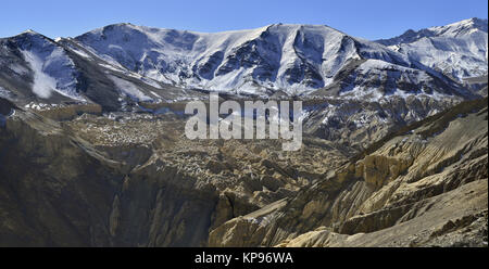 Inverno in montagna: gamme della montagna sono coperti di neve sulle cime, qui di seguito sono di colore giallo e marrone rocce, l'Himalaya. Foto Stock