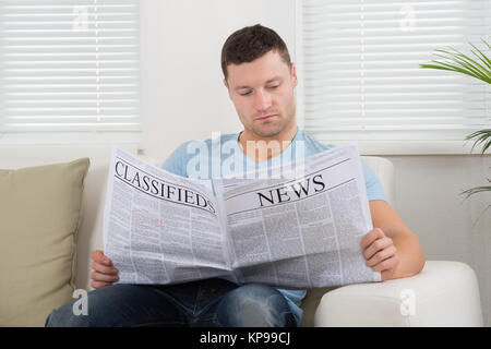 Uomo che legge il giornale a casa Foto Stock