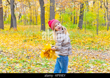 Ragazza carina con mazzi di fogli in autunno Foto Stock