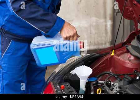 Veterani versando il liquido lavavetri parabrezza in auto Foto Stock