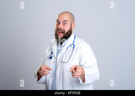 Giovane medico barbuto in camice bianco a sorridere e a puntare la telecamera Foto Stock
