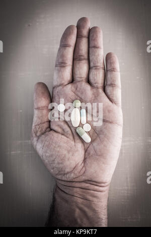 Assortimento di compresse e pillole in una mano d'uomo. Foto Stock