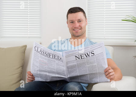 Uomo che legge il giornale a casa Foto Stock