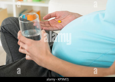 Donna incinta prendendo medicine Foto Stock