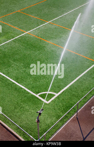 Irrigazione sistema sprinkler lavora al campo sportivo. Il verde colore di sfondo Foto Stock