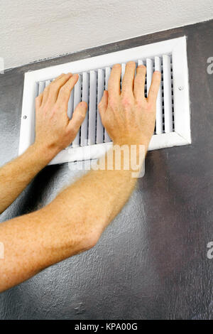 Le mani su uno sfiato di aria Foto Stock
