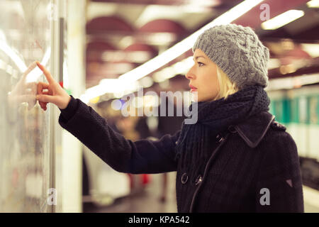 Signora guardando la mappa dei trasporti pubblici pannello. Foto Stock