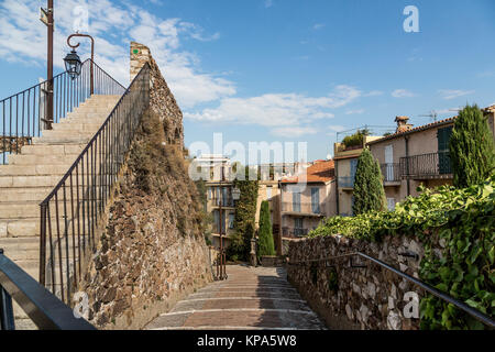 L'accogliente old street con piante verdi in vasi e scarico in mezzo alla strada. Street con edifici e pavimentata in mattoni in passerella di Cannes, Francia Foto Stock