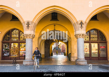 Panno di Cracovia Hall, una giovane donna ciclista emerge dal colonnato del panno medievale Hall nella Piazza del Mercato di Cracovia, in Polonia. Foto Stock