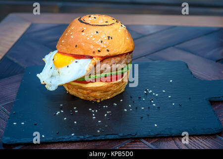 Close up cucinato al momento ristorante burger con uovo nero sul pannello di legno Foto Stock