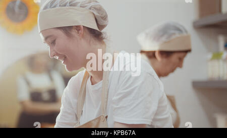 Donna sorridente cuochi sta lavorando sulla cucina Foto Stock