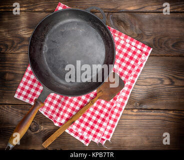 Vuoto nero tondo padella con un manico in legno su uno sfondo marrone, vista dall'alto Foto Stock