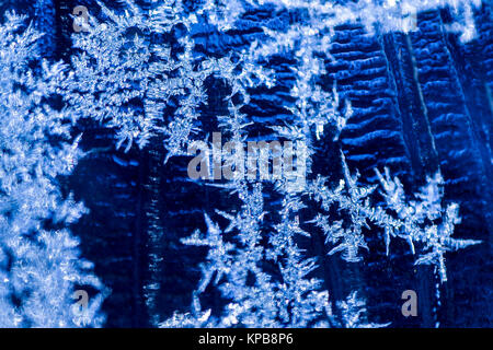 I cristalli di ghiaccio formato sulla finestra contro un freddo sfondo blu Foto Stock