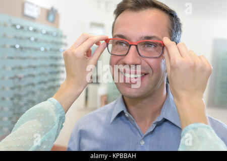 Uomo che guarda nello specchio cercando sui bicchieri Foto Stock