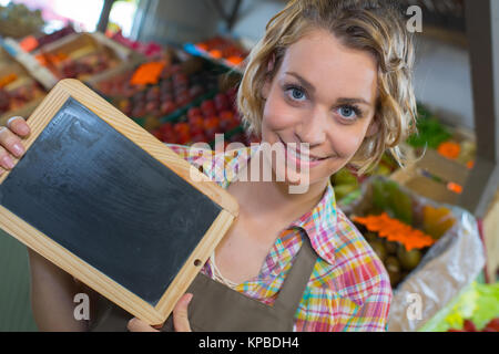 Sorridente personale femminile tenendo la scheda nel supermercato Foto Stock