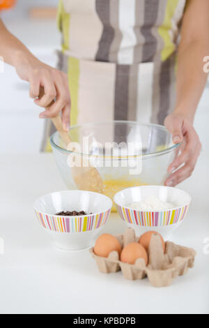 Rottura di un uovo in una ciotola la preparazione di impasti per la cottura Foto Stock