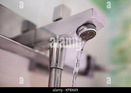 Rubinetto e goccia d'acqua. Flussi di acqua dal rubinetto del bagno. Miscelatore con doccia. getto di acqua potabile pulita. Foto Stock