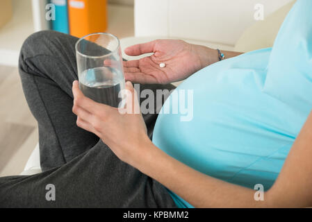 Donna incinta prendendo medicine Foto Stock