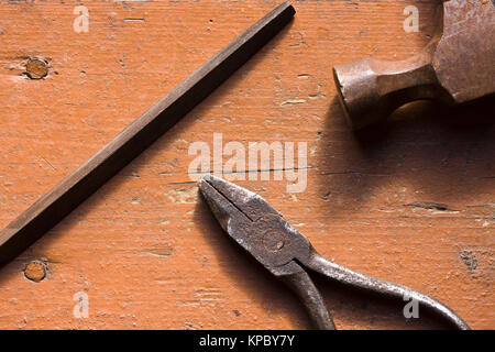 Vecchio arrugginito pinze, file e martello sul banco di lavoro Foto Stock